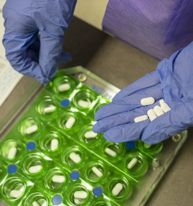 Pharmacy tech placing pills into a pill container